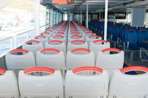 Rows of white boat seats with red handles are arranged in a spacious and orderly manner on a boat. The image showcases a clean, organized seating area with ample room, emphasizing the potential for modifying these boat seats to add convenient storage solutions.